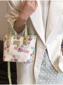 Gros plan du sac cabas imprimé avec poignées vertes et tenue florale sur un mannequin