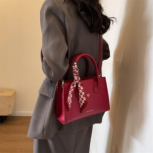 Rote Vintage Handtasche aus Kunstleder mit Seidenschal und goldenem Herz-Logo an Model