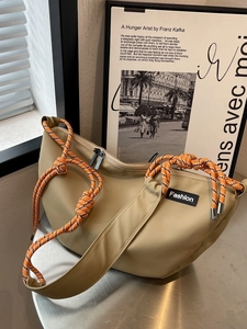 Khaki canvas crossbody bag with orange patterned rope and a fashion label decoration