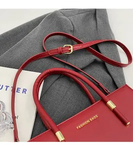 Dettaglio borsa tote rossa con scritta dorata e tracolla regolabile in pelle opaca