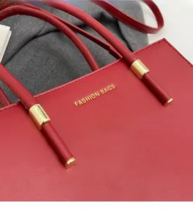 Dettaglio della borsa tote in pelle rossa con logo dorato e finiture in metallo