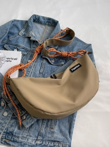 Unisex khaki dumpling crossbody bag with orange climbing rope strap on denim background