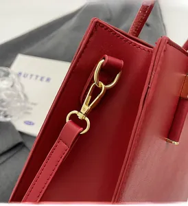 Dettaglio della borsa tote in pelle rossa con fibbia in metallo dorato lucido e cuciture