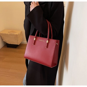 Dettaglio della borsa tote in pelle rossa con logo dorato e finitura in materiale pregiato