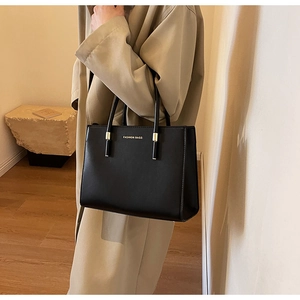 Dettaglio borsa shopper nera con scritte dorate Fashion Bags su espositore minimalista