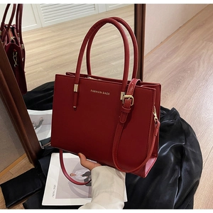 Dettaglio della borsa tote rossa con finiture dorate e riflesso specchiato elegante