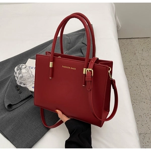 Dettaglio della borsa tote rossa in pelle con fibbia dorata e scritta Fashion Bags