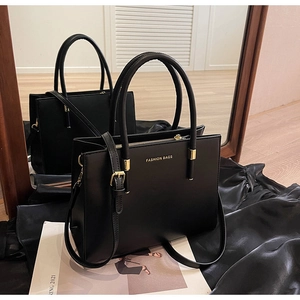 Dettaglio della borsa tote nera opaca con logo dorato, doppi manici e tracolla rimovibile