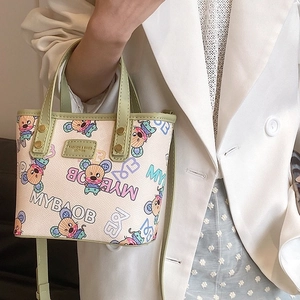 Mini sac cabas imprimé cartoon avec poignées en cuir vert sur une veste de blazer blanc