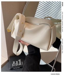 Detail view of cream leather shoulder bag side featuring gold studs and brand lettering