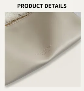 Detail view of the cream leather handbag featuring embossed logo and gold zipper closure