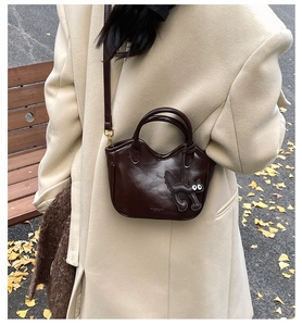 Detail of premium oil wax leather basket bag with a cute black cat charm accessory