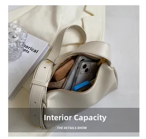 Internal capacity of minimalist off-white shoulder bag showing phone and wallet