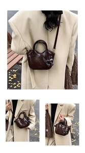 Detail of dark brown wax leather tote with unique wave opening and cat pendant