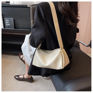 Detail of a creamy white pleated shoulder bag in soft faux leather with golden zipper