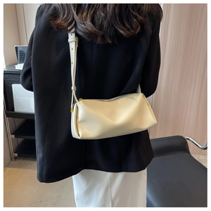 Detail of cream white leather crossbody bag showing texture and adjustable strap on a model