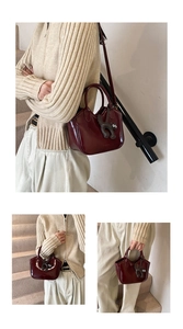 Burgundy oil wax leather bucket bag with cute cat charm worn on shoulder and hand