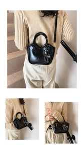 Three-way view of a black oil-wax leather tote bag with a cute cat charm detail