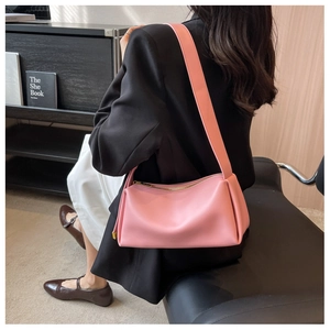 Detailed view of pink matte leather shoulder bag with wide strap and gold zipper