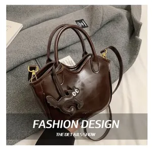 Detailed shot of brown oil wax leather tote bag with a cute cat charm accessory