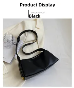Close-up of black leather shoulder bag with gold metal corners and minimalist design
