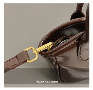 Detail of high-quality golden metal hook and shiny dark brown leather strap on tote bag