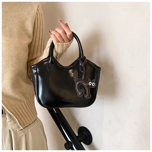 Detail of glossy wax leather bucket bag with cute cat charm and chic top handle