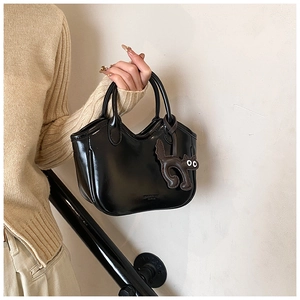 Detailed view of black oil wax leather tote bag with a cute cat charm accessory
