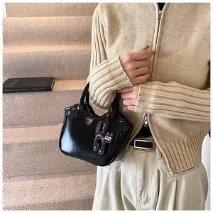 Close-up of black glossy oil wax leather tote bag with a cute black cat charm on stairs
