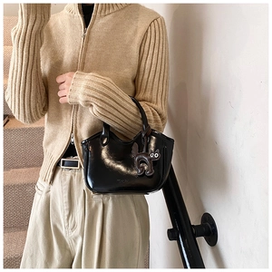 Close-up of a glossy oil wax leather tote bag with a cute black cat charm accessory