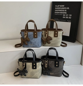 Detail of trendy bucket bags in four colors with leather trim and dog-shaped charm