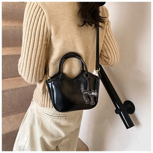 Detail of black oil wax leather tote bag with a cute cat charm on minimalist stairs