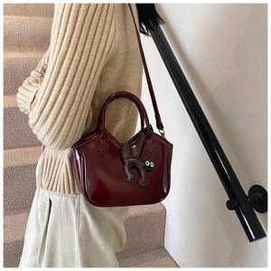 Detail view of deep wine red oil wax leather handbag with a cute cat charm accessory