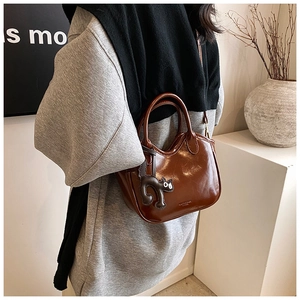 Brown oil wax leather bucket bag with black cat charm and detachable shoulder strap