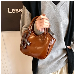 Detailed shot of brown vintage oil wax leather tote featuring a black cat leather charm