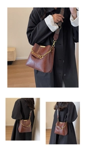 Details der braunen Vintage-Eimertasche mit Goldkette und Ethno-Schultergurt