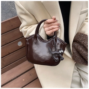 Close-up of gloss leather handbag with MICOCAH logo and cat charm detail
