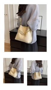 Detail der cremefarbenen Beuteltasche mit goldener Kette und bedrucktem breitem Riemen