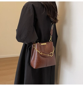 Detail der Vintage dunkelbraunen Beuteltasche mit Goldkette, getragen von einem Modell