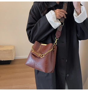 Details der Vintage-Eimertasche aus braunem Leder mit gewebtem Riemen und Goldkette