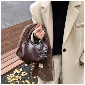 Detail of oil wax leather tote bag with cute cat charm in an autumn setting