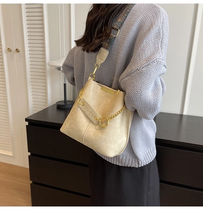 Detailsicht der cremefarbenen Beuteltasche mit besticktem Gurt und goldener Kette