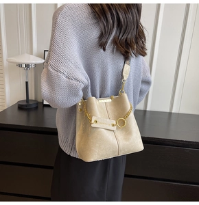 Beige PU-Leder Beuteltasche mit Metallkette und bedrucktem Gurt an Model-Schulter gezeigt
