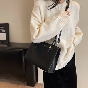 Borsa tote nera minimalista con scritte dorate indossata da una modella in scena