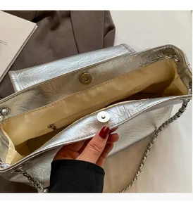 Detailed view of silver shoulder bag's beige interior lining and magnetic snap closure