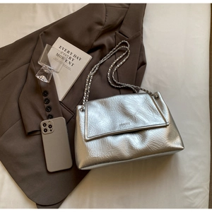Detail of silver metallic wrinkled bag with chain strap on a blazer flat lay