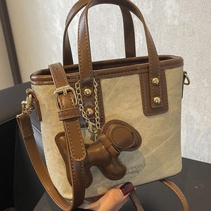 Mini canvas and brown leather bucket bag with dog charm and gold hardware detail
