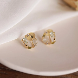 Macro shot of wreath-shaped invisible clip earrings with colorful opal and zircon gems
