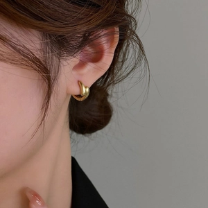 Orecchini a cerchio irregolari in oro opaco vintage su modella femminile