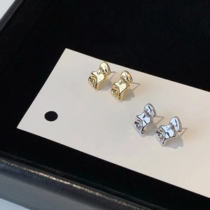 Irregular wave geometric stud earrings in gold and silver finish on white display card